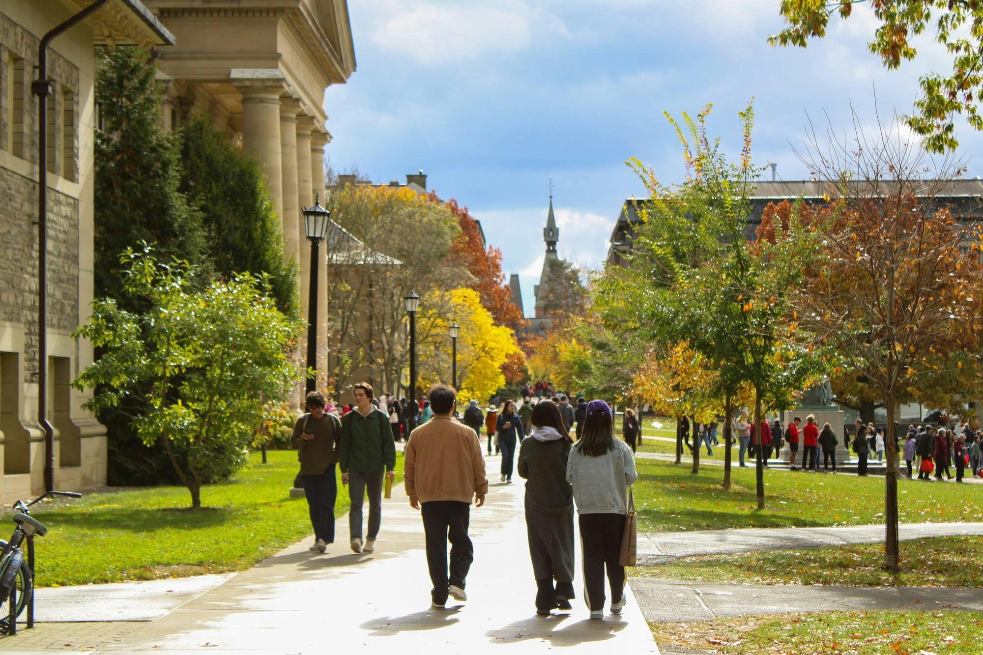 Students walking across a sunlit University campus in autumn